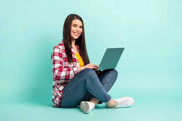 Pełny rozmiar zdjęcie atrakcyjne słodkie młoda kobieta siedzieć podłogi trzymać laptop izolowany na pastelowym tle teal kolor — Zdjęcie stockowe