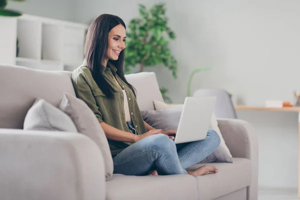 Полный профиль тела стороне фото молодой женщины счастливой позитивной улыбкой сидеть диван смотреть смотреть ноутбук в помещении — стоковое фото