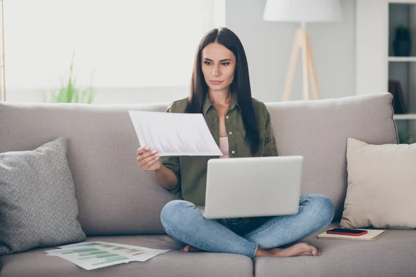 Portrét okouzlující kvalifikované soustředěný dívka sedí na pohovce pomocí notebooku čtení dokumentů pracuje dálkově doma byt krytý — Stock fotografie