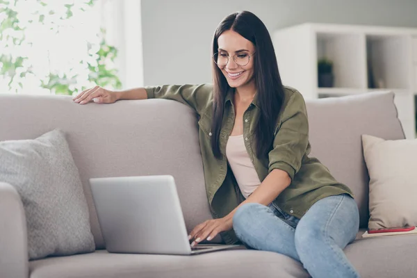 Full body profil boczny zdjęcie młodej kobiety szczęśliwy pozytywny uśmiech siedzieć kanapa wygląd przeglądać laptop praca projekt w pomieszczeniach — Zdjęcie stockowe