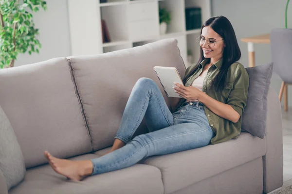 Foto lateral de perfil de longitud completa de mujer atractiva joven sonrisa positiva feliz escribir cuaderno plan de lista de tareas de sofá en el interior —  Fotos de Stock