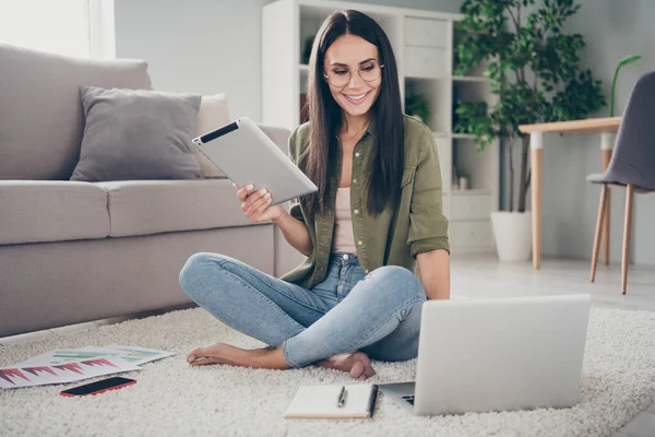 Retrato de cuerpo completo de encantadora persona alegre sentarse en la tableta de sujeción del piso mirada portátil tiene buen humor de trabajo desde casa en el interior —  Fotos de Stock