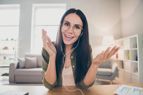 Foto av ung glad positiv leende glad gott humör kvinna i glasögon och hörlurar har videosamtal hemma hus — Stockfoto
