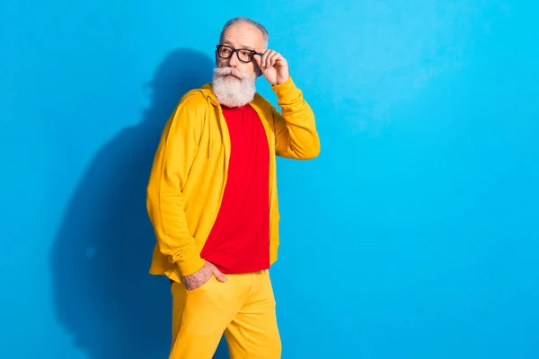 Foto av allvarliga cool säker stilig mogen man i glasögon ser copyspace gå promenad isolerad på blå färg bakgrund — Stockfoto