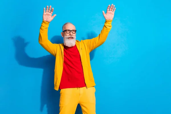 Photo funky drôle souriant homme mûr dans des lunettes dansant en s'amusant porter costume jaune isolé sur fond de couleur bleue — Photo