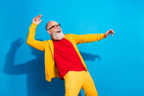 Foto de funky divertido buen humor alegre hombre maduro en gafas bailando disfrutando de fin de semana aislado sobre fondo de color azul —  Fotos de Stock