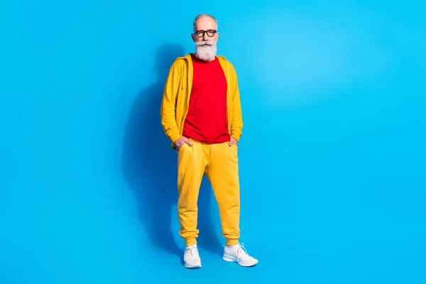 Full size photo of mature handsome good looking serious man wear yellow tracksuit isolated on blue color background — Stock Photo, Image
