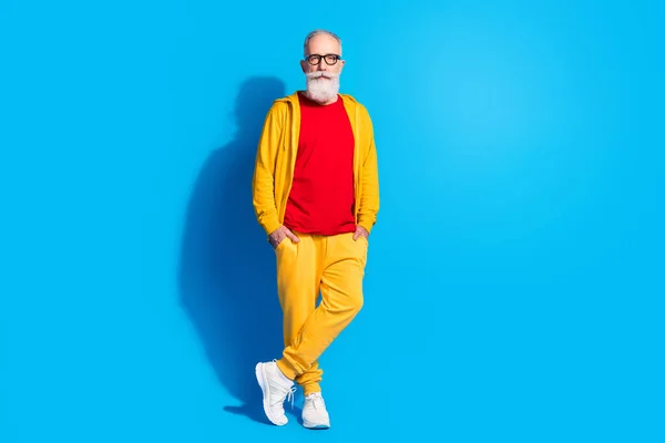Foto de tamaño completo de guapo abuelo serio de mente reflexiva en ropa deportiva amarilla aislado sobre fondo de color azul —  Fotos de Stock