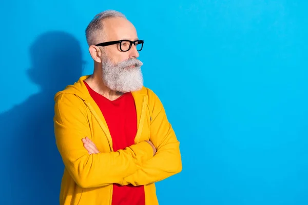 Photo of focused representative mature man in glasses look copyspace with crossed arms isolated on blue color background — Stock Photo, Image
