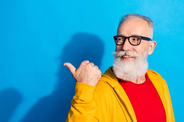 Photo of happy smiling positive mature man in glasses point finger copyspace advertisement isolated on blue color background — Stock Photo, Image