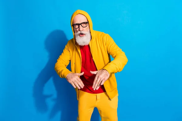 Foto de hombre maduro divertido divertido funky en gafas de baile usan chándal amarillo aislado sobre fondo de color azul —  Fotos de Stock