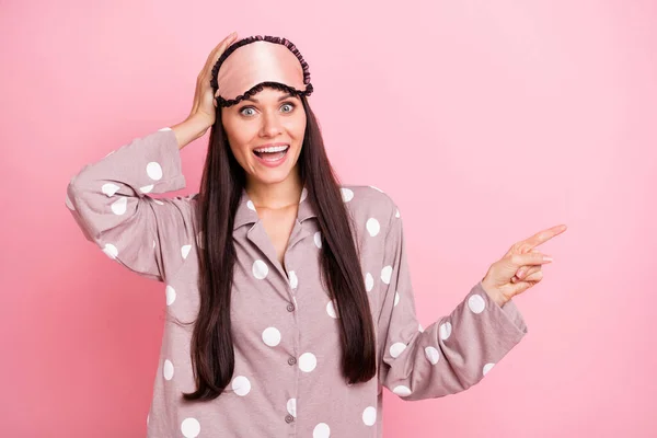 Foto de mujer joven divertida impresionada punteada máscara de dormir brazo cabeza señalando el dedo vacío espacio aislado color rosa fondo —  Fotos de Stock