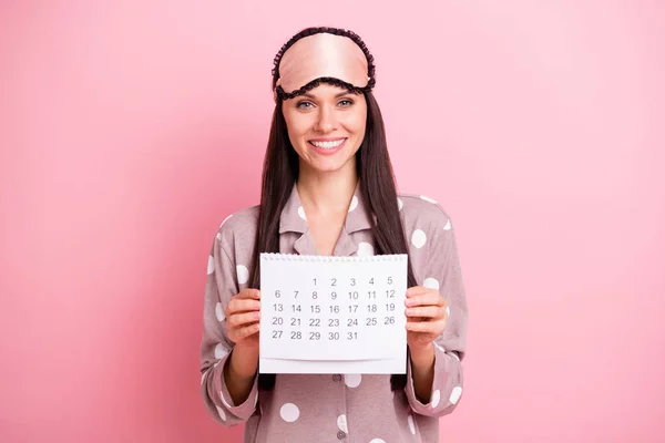 Foto de bastante encantadora joven ropa de dormir celebración de papel calendario aislado color rosa fondo —  Fotos de Stock