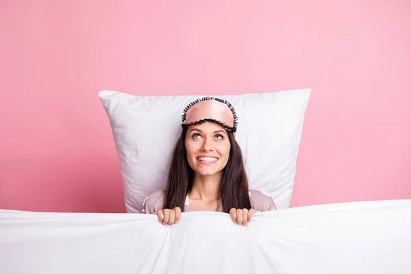 Photo of adorable shiny young lady nightwear mask covering blanket lying pillow looking empty space isolated pink color background — Stock Photo, Image