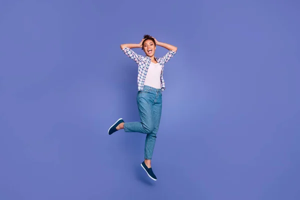 Fénykép vicces lenyűgözött fiatal hölgy öltözött kockás jumping magas karok fej elszigetelt lila szín háttér — Stock Fotó