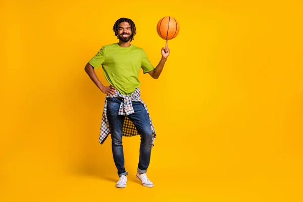 Pełna długość zdjęcie portret człowieka wirujący koszykówka na palcu izolowane na żywe żółte tło — Zdjęcie stockowe