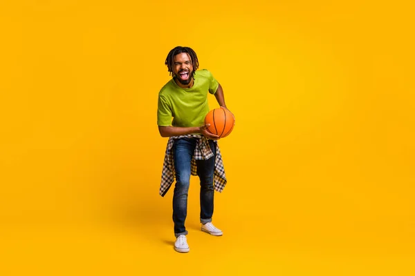 Foto retrato vista de cuerpo completo del chico riendo sosteniendo la pelota aislado sobre fondo de color amarillo vivo — Foto de Stock