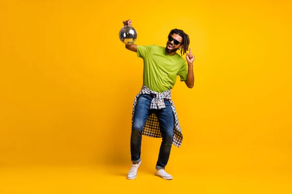 Foto de longitud completa de la danza joven loco hombre disfrutar de fiesta de música celebrar la bola de brillo pantalones vaqueros aislados sobre fondo de color amarillo —  Fotos de Stock