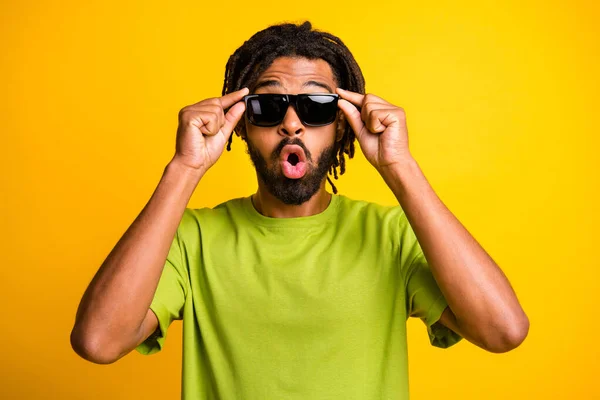 Фото молодого африканца, удивлённого шокированным слухом о прикосновении солнцезащитных очков на жёлтом фоне — стоковое фото