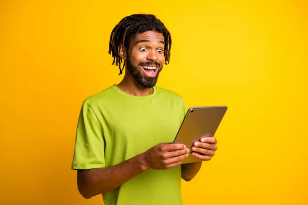 Foto de hombre joven utilizar tableta dispositivo moderno leer sorprendido noticias emocionadas información aislada sobre fondo de color amarillo —  Fotos de Stock