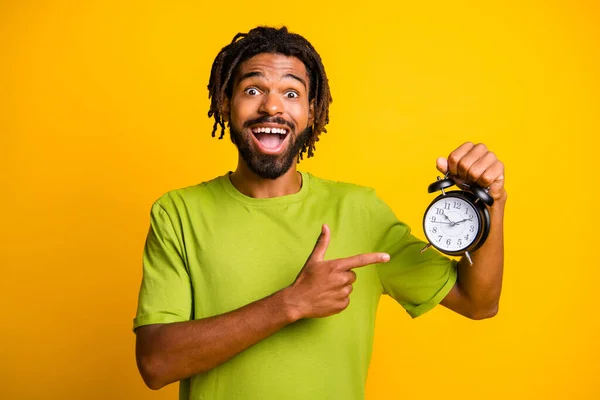 Fénykép a fiatal afro man boldog pozitív izgatott ámult show pont ujj óra riasztás elszigetelt sárga szín háttér — Stock Fotó