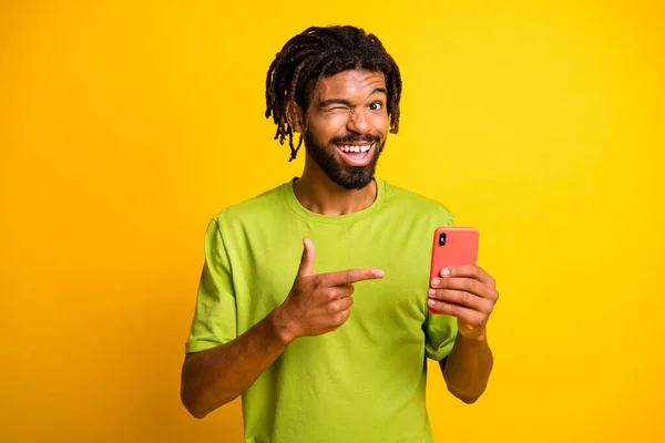 Фото збудженого темної шкіри хлопець рекомендує соціальні медіа реклами точковий смартфон носити футболку ізольовані на блискучому кольоровому фоні — стокове фото