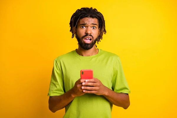 Foto di stupefatto pazzo ragazzo pelle scura tenere smartphone antipatia feedback concetto isolato su sfondo colore giallo lucido — Foto Stock