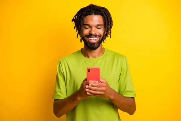 Foto de chico positivo de piel oscura usar el teléfono celular leer noticias de redes sociales aisladas sobre fondo de color ahine brillante — Foto de Stock