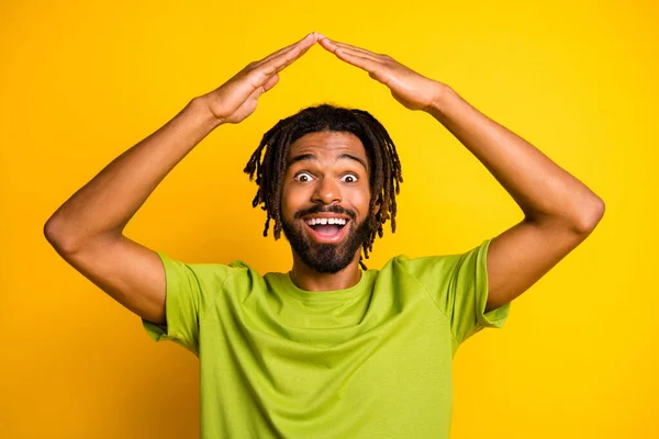 Sorprendido chico de piel oscura de la cabeza de la mano nuevo concepto de la casa llevar camiseta verde aislado sobre fondo de color amarillo —  Fotos de Stock
