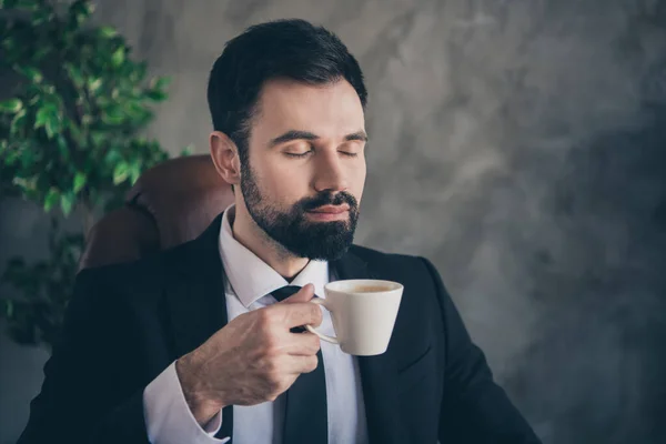 Foto van ontspannen koele zakenman houden mok geur koffie aroma slijtage pak shirt das in modern kantoor binnen — Stockfoto