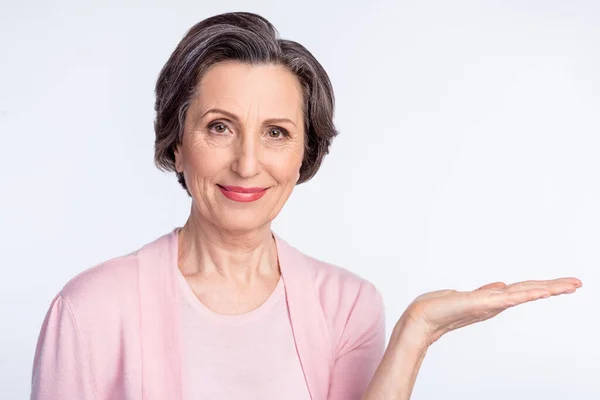 Photo de femme âgée heureux sourire positif montrer main produit promo offre isolé sur fond de couleur grise — Photo
