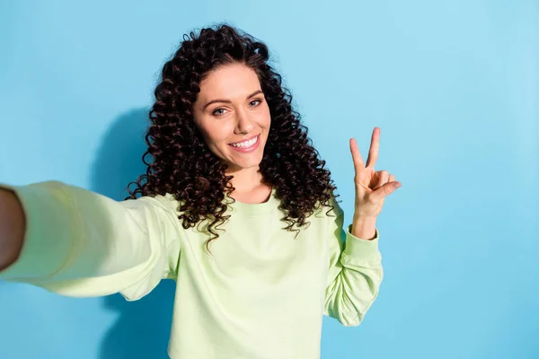 Retrato de chica bastante positiva hacer selfie dedos muestran v-signo toothy sonrisa aislada sobre fondo de color azul —  Fotos de Stock