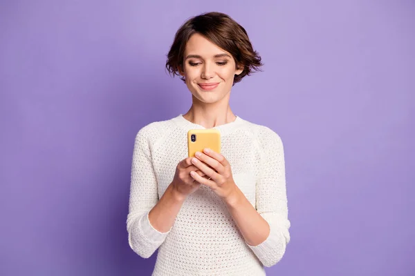 Foto retrato de alegre chica morena feliz usando suéter sonriendo con teléfono inteligente aislado sobre fondo de color púrpura pastel —  Fotos de Stock