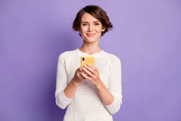 Фотопортрет улыбающейся позитивной женщины, держащей смартфон изолированным на фиолетовом фоне — стоковое фото