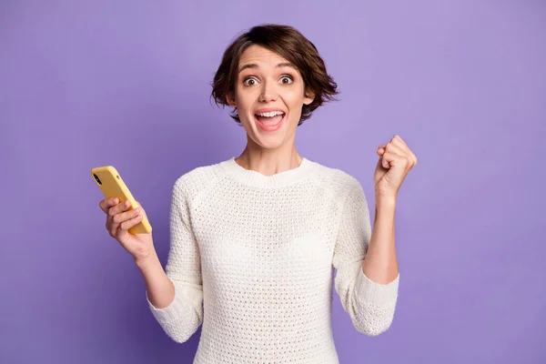Фотопортрет щасливої насолодженої жінки-блогера з жестом мобільного телефону, як переможець, ізольований на яскраво-фіолетовому кольоровому фоні — стокове фото
