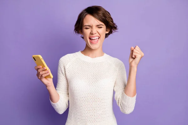 Фотопортрет щасливої кричущої брюнетки з жестом смартфона, як переможець, ізольований на яскраво-фіолетовому кольоровому фоні — стокове фото