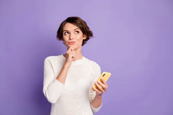 Photo portrait of dreamy female brunette looking at empty space with cellphone thinking isolated on vibrant violet color background — Stock Photo, Image