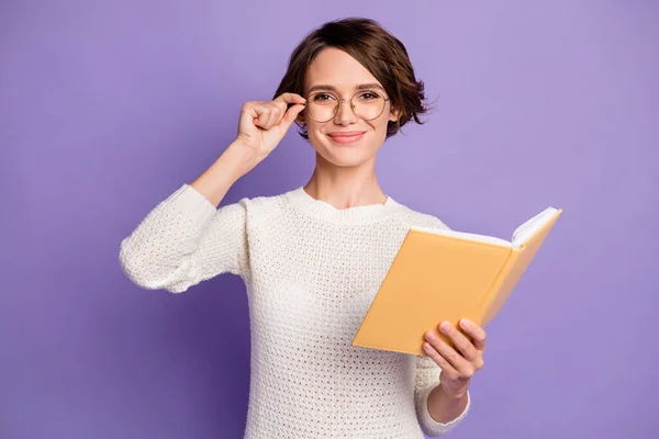 Foto portrét chytré studentky dotýkající se brýlí vedení knihy izolované na jasně fialové pozadí — Stock fotografie