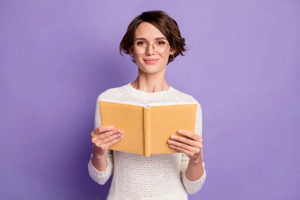 Фотографічний портрет розумної студентки, яка посміхається з книгою в окулярах ізольовано на яскравому фіолетовому кольоровому фоні — стокове фото