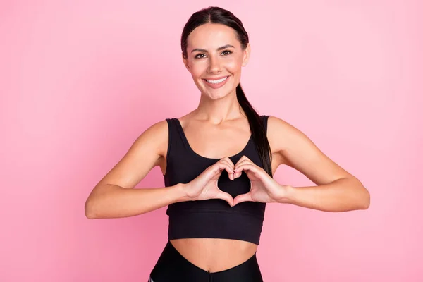 Foto de adorable feliz mujer bastante deportivo cogido de la mano muestran la forma del corazón aislado en el fondo de color rosa —  Fotos de Stock