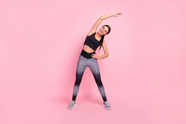 Foto de longitud completa de la mujer joven levantar la mano mantenga la cintura caliente gimnasia aislada sobre fondo de color rosa —  Fotos de Stock