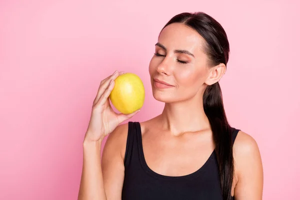 Foto av ganska drömmande ung kvinna klädd sportig outfit njuter äpple lukt slutna ögon ler isolerad rosa färg bakgrund — Stockfoto