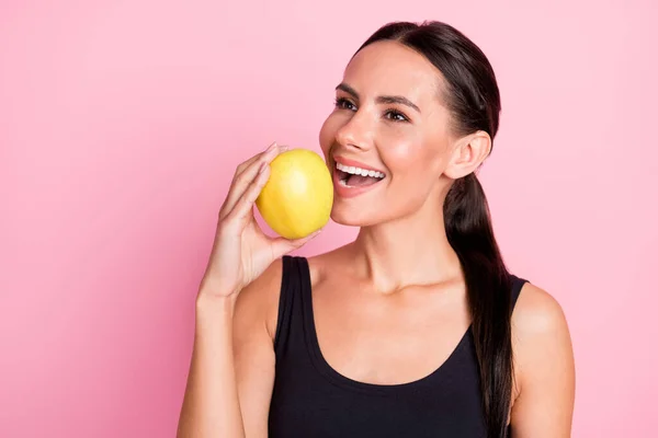 Foto de adorable joven alegre ropa deportiva sonriente manzana mordida buscando espacio vacío aislado color rosa fondo —  Fotos de Stock