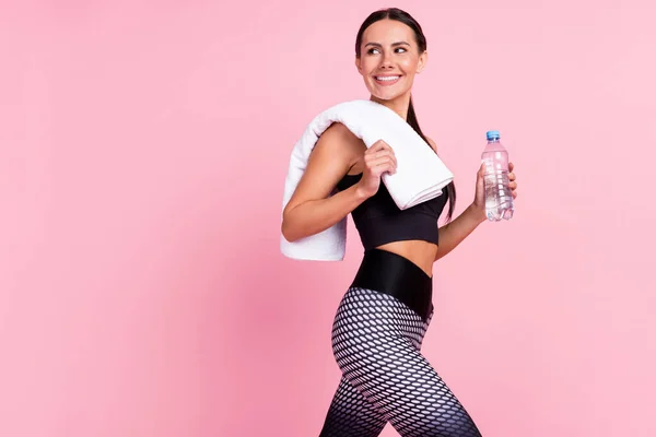 Foto de adorable dulce joven ropa deportiva caminar sosteniendo botella de agua mirando hacia atrás espacio vacío aislado color rosa fondo —  Fotos de Stock