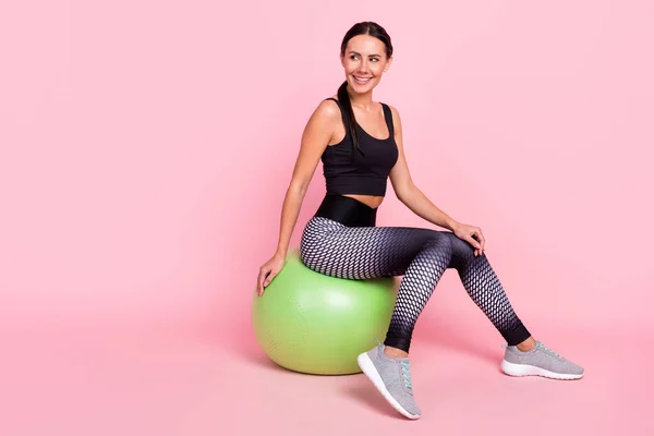 Foto von ziemlich glänzend junge Dame Sportbekleidung mit Ruhe großen grünen fit Ball lächelnd suchen leeren Raum isoliert rosa Farbe Hintergrund — Stockfoto