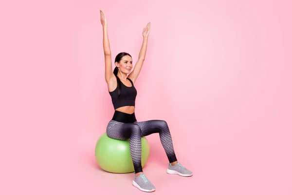 반짝이는 매력적 인 여성 스포츠 용품 점에 앉아 큰 초록색 공을 던지며 함성을 지르는 사진빈 공간을 바라보고 있는 핑크 색 배경 — 스톡 사진