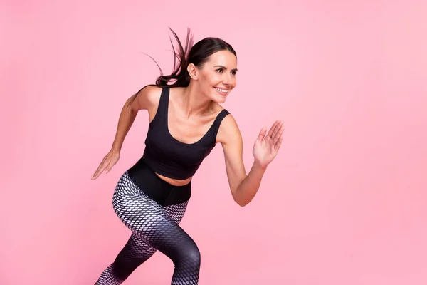 Foto del lado del perfil de la joven mujer deportiva feliz sonrisa positiva ejecutar entrenamiento cruzado rápido aislado sobre fondo de color pastel —  Fotos de Stock