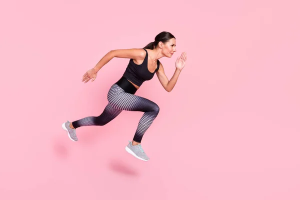 Foto lateral de perfil de longitud completa de la joven mujer deportiva ir a pie correr salto rápido competición cruzada aislado sobre fondo de color pastel — Foto de Stock