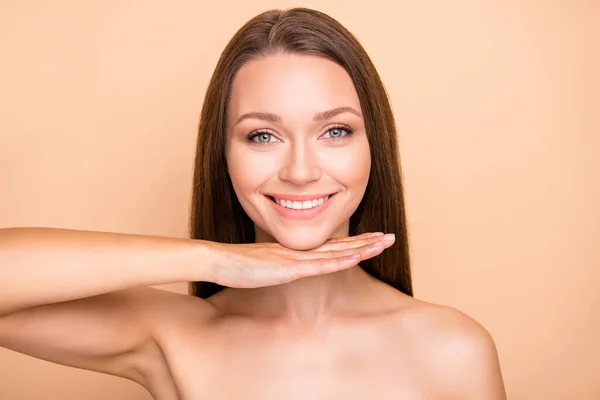 Foto de joven alegre chica mano bajo barbilla sonrisa positiva feliz procedimiento de cosmetología levantamiento aislado sobre fondo de color beige —  Fotos de Stock