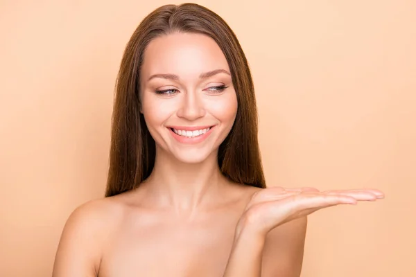 Porträt eines hübschen fröhlichen Mädchens, das auf der Handfläche Kopierraum hält und sich über beige Pastellfarben verwöhnen lässt — Stockfoto